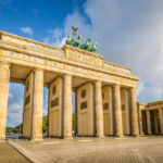 Famous Brandenburger Tor (Brandenburg Gate), one of the best-known landmarks and national symbols of Germany, in beautiful golden morning light at sunrise with lens flare effect, Berlin, Germany.
